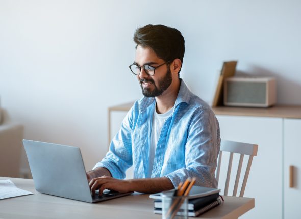 Millennial arab freelancer man working online on laptop at home office